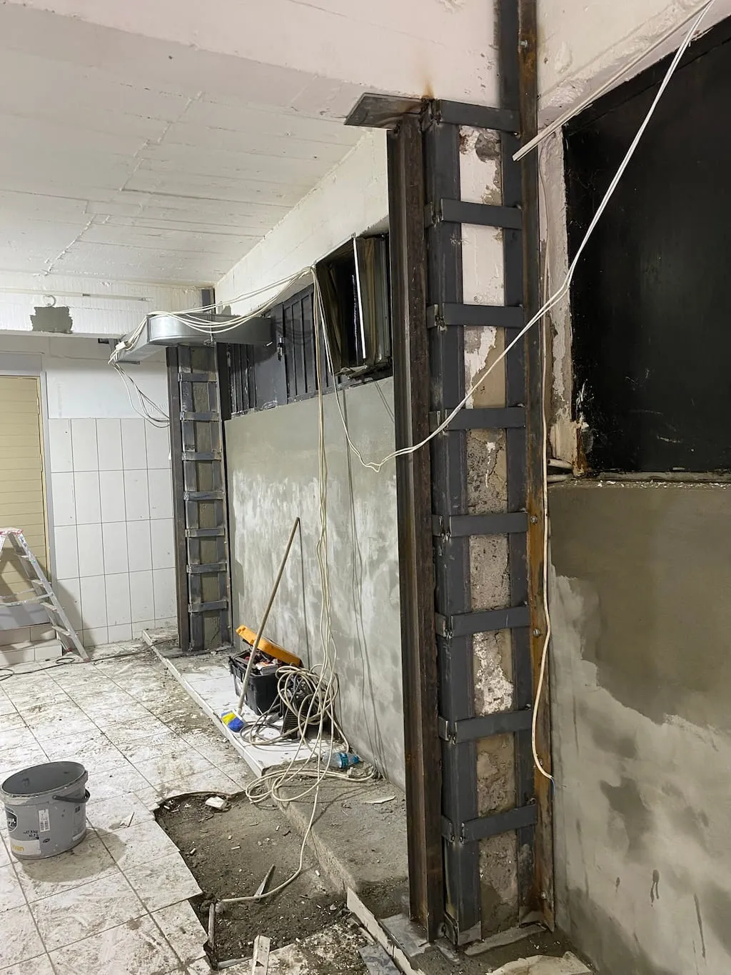 Köşebent ve lamalarla mantolanarak güçlendirilmiş iki betonarme kolon, tadilat aşamasındaki iç mekân