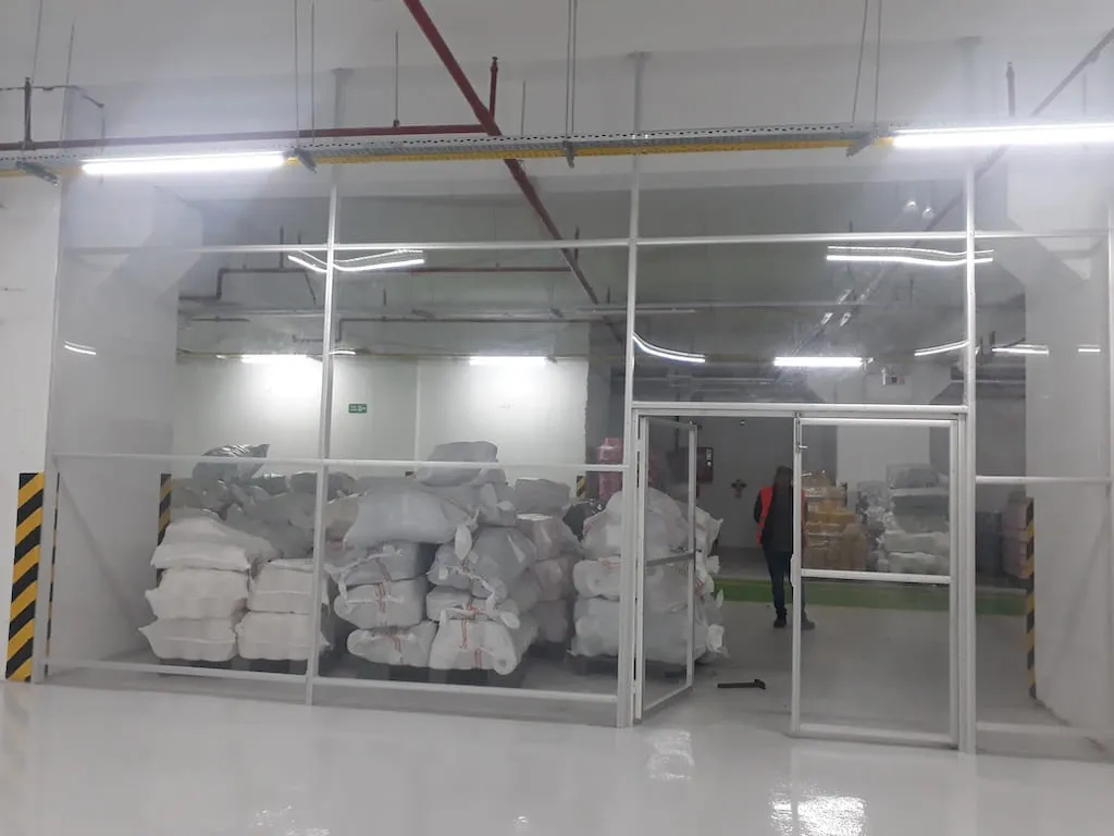 Otopark katında beyaz çelik profil ve camla yapılan depo bölmesi ile camlı çelik kapı