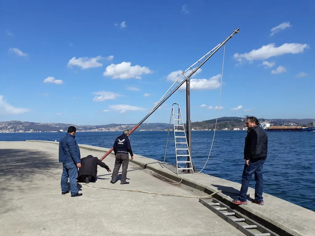 Boğaz kıyısındaki iskelede çelik direk ve vinç kolu montajı yapan ekip