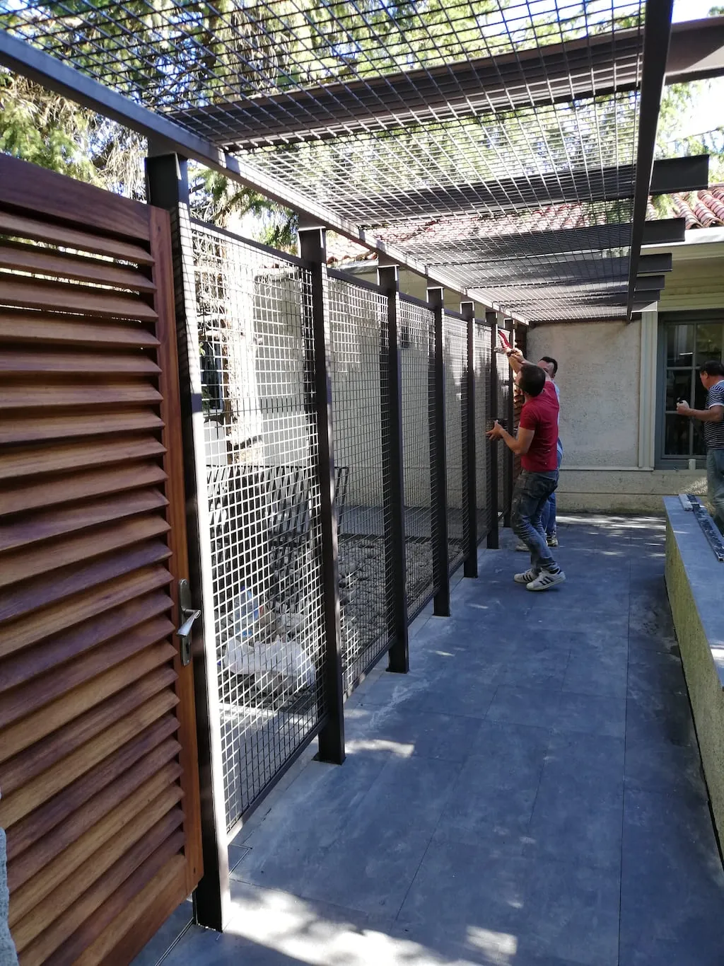 Bahçede kurulan çelik konstrüksiyon pergola ve hasır tel panellerini monte eden ustalar
